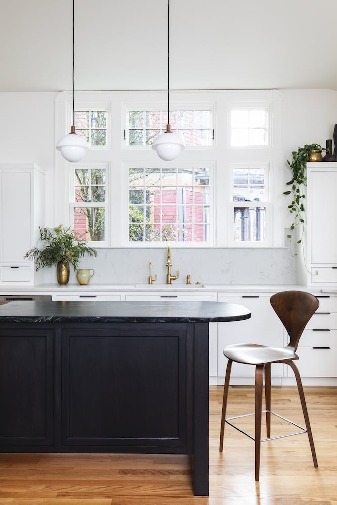 Remodeled traditional white kitchen with wood floors, black island, pendant lights