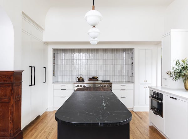 Traditional white kitchen with black curved island, range alcove, and pendant lights