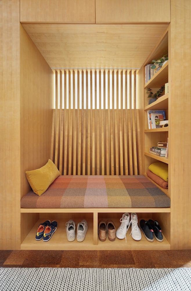 Custom wood slat reading nook with natural light and thoughtful storage design